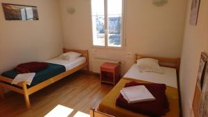 2 camas en una habitación pequeña con ventana en APF France handicap - Ferme Léonie, en Saint-Laurent-en-Grandvaux