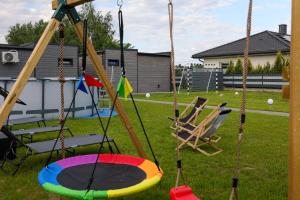 a swing set in a yard with two chairs at Jej i Jego - Eleganckie domki z balią na wyłączność in Niewiesze