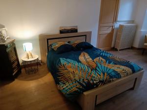 ein Schlafzimmer mit einem Bett mit blauer Decke und einer Lampe in der Unterkunft L'écrin in Lacroisille