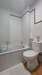 y baño blanco con aseo y bañera. en Villa Xunqueira 2, en Cee