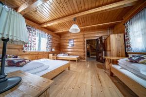 Dormitorio en cabaña de madera con 2 camas y escritorio en Domek Góralski, en Piwniczna-Zdrój
