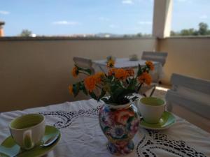 奥尔比亚La Casa dei Fenicotteri的花瓶,桌子上放着橙花,有两杯