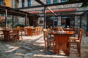a restaurant with wooden tables and chairs in front of a building at Pliades Traditional Guesthouse in Palaios Panteleimon