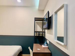 a room with a bed and a table and a tv at Smile Hotel Subang USJ in Subang Jaya