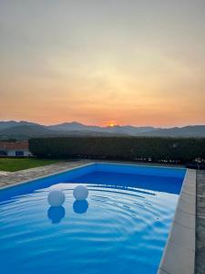uma piscina azul com um pôr-do-sol ao fundo em VILLA FRANCESCA em Tanaunella