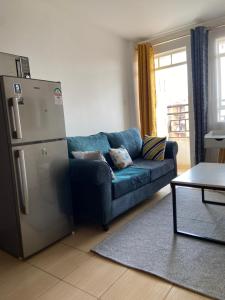 Comfy One Bedroom Apartment at Joyland Ruaka في Ruaka: غرفة معيشة بها أريكة زرقاء وثلاجة