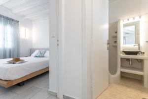 a bedroom with a bed and a sink and a mirror at Caruana Inland Naxos in Agia Anna Naxos