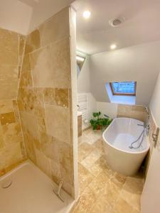 La salle de bains est pourvue d'une grande baignoire et d'une douche. dans l'établissement La casa Terracotta - centre ville , spacieux & confortable, à Béthune