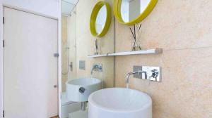 ein Bad mit einem Waschbecken und einem Wandspiegel in der Unterkunft Fitzrovia Apartment By Morethanstays in London