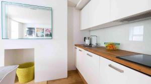 eine Küche mit weißen Schränken und einer Arbeitsplatte in der Unterkunft Fitzrovia Apartment By Morethanstays in London
