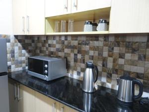a kitchen counter with a toaster and a microwave at Sami BnB - Apt 01 Makongo after Mlimani City in Dar es Salaam