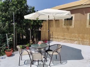 a table and chairs under an umbrella on a patio at CORFU FOTIS house in Neochorákion
