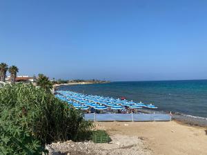 a beach with many blue umbrellas and the ocean at Casa di Sara&Anna in Avola