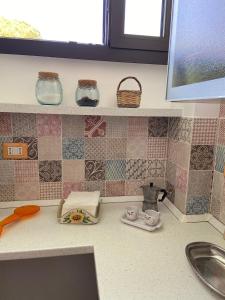 eine Küchentheke mit Spüle und Wandfliesen in der Unterkunft Casa Salento in Specchia
