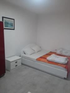 a white bedroom with a bed and a night stand at River Hostel Belgrade in Belgrade