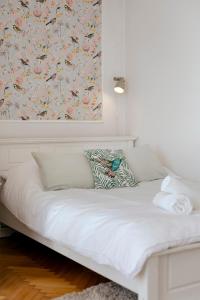 uma cama branca num quarto com papel de parede floral em Gagarina 12 - Piękny apartament przy Łazienkach Królewskich - Duże łóżko 160x200cm - Bardzo duży balkon - Wifi - Telewizja kablowa - Bezpłatna strefa parkowania - Better Rental em Varsóvia