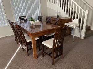 a wooden dining room table with chairs and a staircase at 4BR House for Whole Family in Schofields