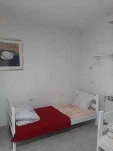 a white bedroom with a bed with a red blanket at River Hostel Belgrade in Belgrade