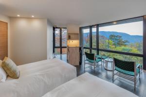 a bedroom with two beds and a large window at KANAYA RESORT HAKONE in Hakone