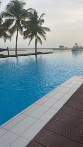 a swimming pool with palm trees in the background at HAWANA RESORT VILLA in Salalah