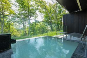 einen Pool mit Blick auf die Bäume in der Unterkunft KANAYA RESORT HAKONE in Hakone