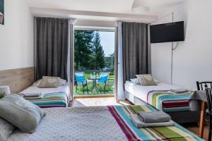 a bedroom with two beds and a balcony with a view at Ruciane Tarasy in Ruciane-Nida