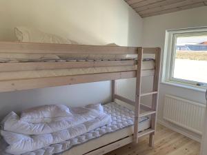 a bunk bed room with two bunk beds next to a window at Moderne sommerhus, 8 senge, 250 mtr til sandstrand in Slagelse