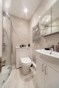 a white bathroom with a toilet and a sink at Kensington luxury flat with patio in London