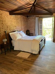 a bedroom with a bed and a brick wall at Vila Adega Maravilha in São Roque