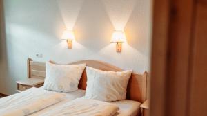 a bedroom with a bed with two pillows and two lights at SONNE Wilhams in Missen-Wilhams