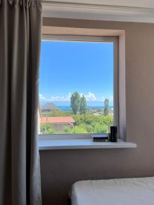 a window in a bedroom with a view of the ocean at Guest house Hygge in Cholpon-Ata