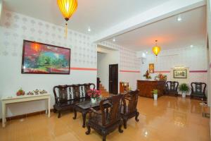 sala de estar con sillas, mesa y una pintura en Cua Dai Beach Homestay, en Hoi An