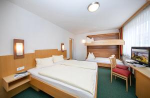 Un dormitorio con una cama, un escritorio y un televisor. en Gästehaus Rudolfo, en Zell am See