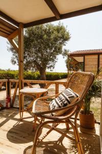 einem Korbstuhl auf einer Terrasse mit einem Tisch in der Unterkunft Dreamsea Bungalows Alentejo in Porto Covo