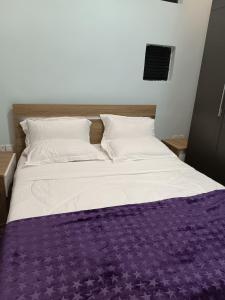 a large bed with a purple blanket on it at TWINS VILLA SUITES KIGALI in Kigali