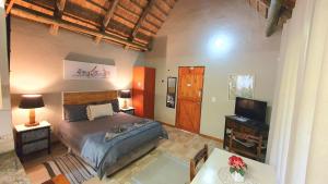 a bedroom with a bed and a flat screen tv at Wild Forest Inn in Graskop