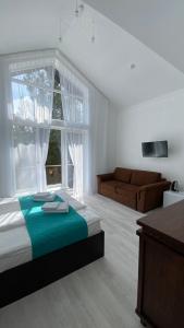 a bedroom with a bed and a couch and a window at DACHA на Магурі in Pilipets