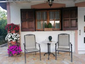 a patio with two chairs and a table and flowers at Tota's guest house, 4 min walk to the beach in Levendokhórion