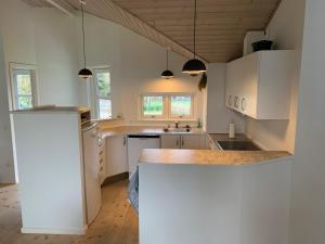 a kitchen with white cabinets and a counter top at Moderne sommerhus, 8 senge, 250 mtr til sandstrand in Slagelse