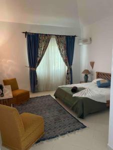 ein Schlafzimmer mit einem Bett, einem Stuhl und einem Fenster in der Unterkunft Villa avec piscine privée in Tabarca