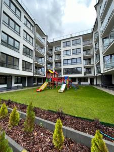 an apartment yard with a playground in front of a building at Apartament za wydmami in Rowy