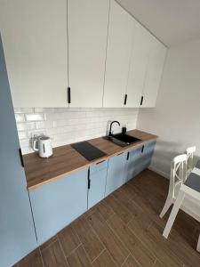een keuken met witte kasten en een wastafel bij Apartament za wydmami in Rowy