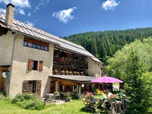 a building with a table and an umbrella in front of it at Le Chalet Viso in Arvieux