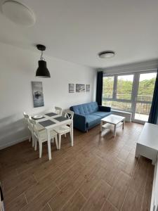 een woonkamer met een blauwe bank en een tafel bij Apartament za wydmami in Rowy