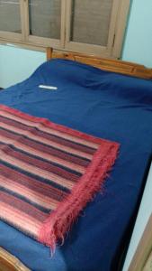 Una cama azul con una alfombra roja y blanca. en LA MAGA en 