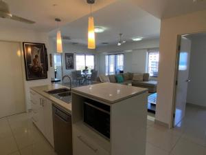 a kitchen with a sink and a living room at Katara On Smith - 2 Bed 2 Bath CBD Appartment in Darwin