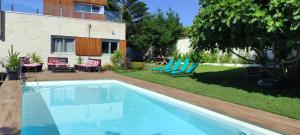 uma piscina em frente a uma casa com cadeiras azuis em Casa playa La Solana en Nigran em Nigrán