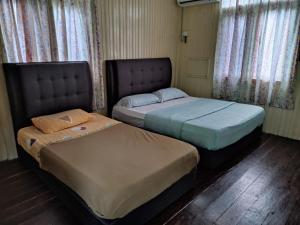two beds sitting next to each other in a room at Mgh Marang guest house in Kampong Kijing