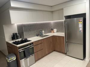 a kitchen with a stainless steel refrigerator and a sink at Mulberry 2BR-2BA Rooftop Pool, BBQ, WiFi & Netflix - Central Location in Canberra