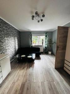 a living room with a black couch and wooden floors at Apartament Ksiazeca in Jelenia Góra